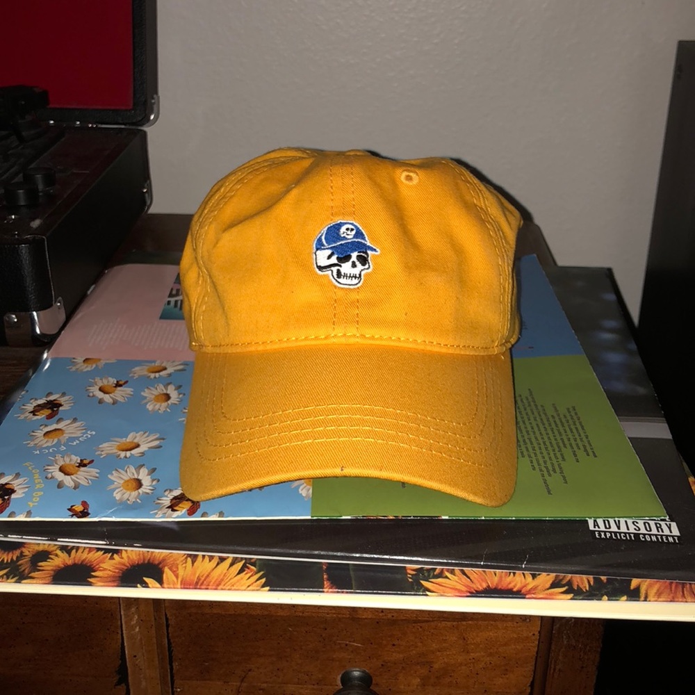 yellow dad hat, with a skullhead